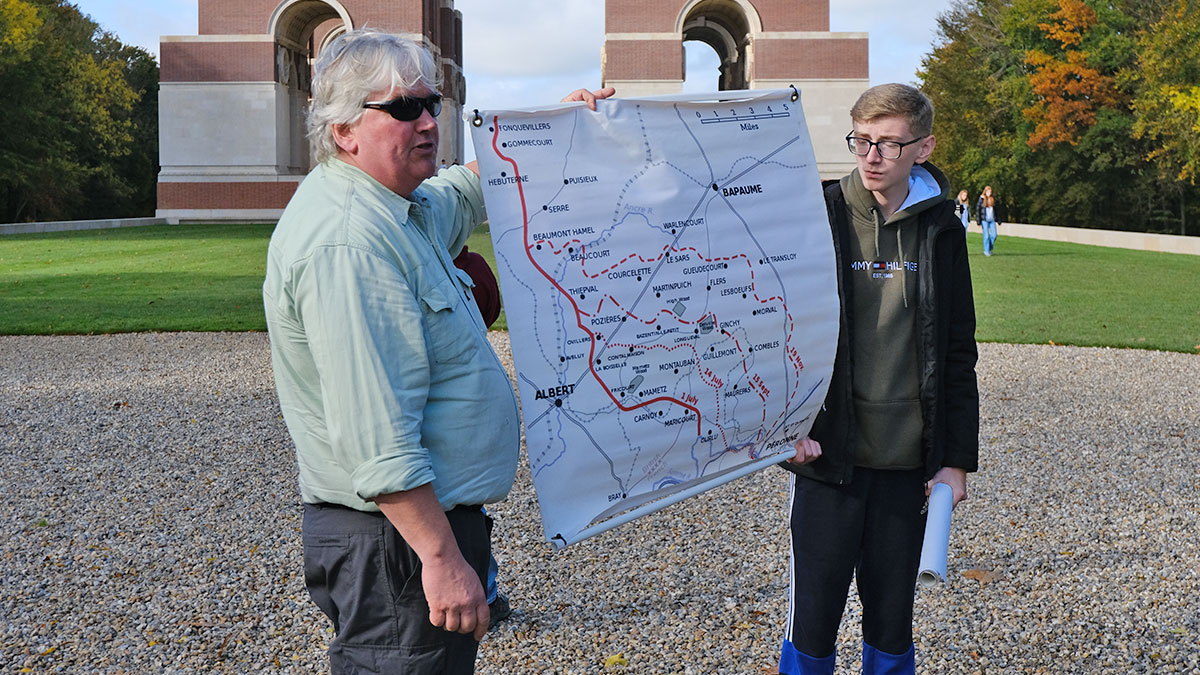 History Tour Guide and students hold map of Western Front with Thiepval Memorial