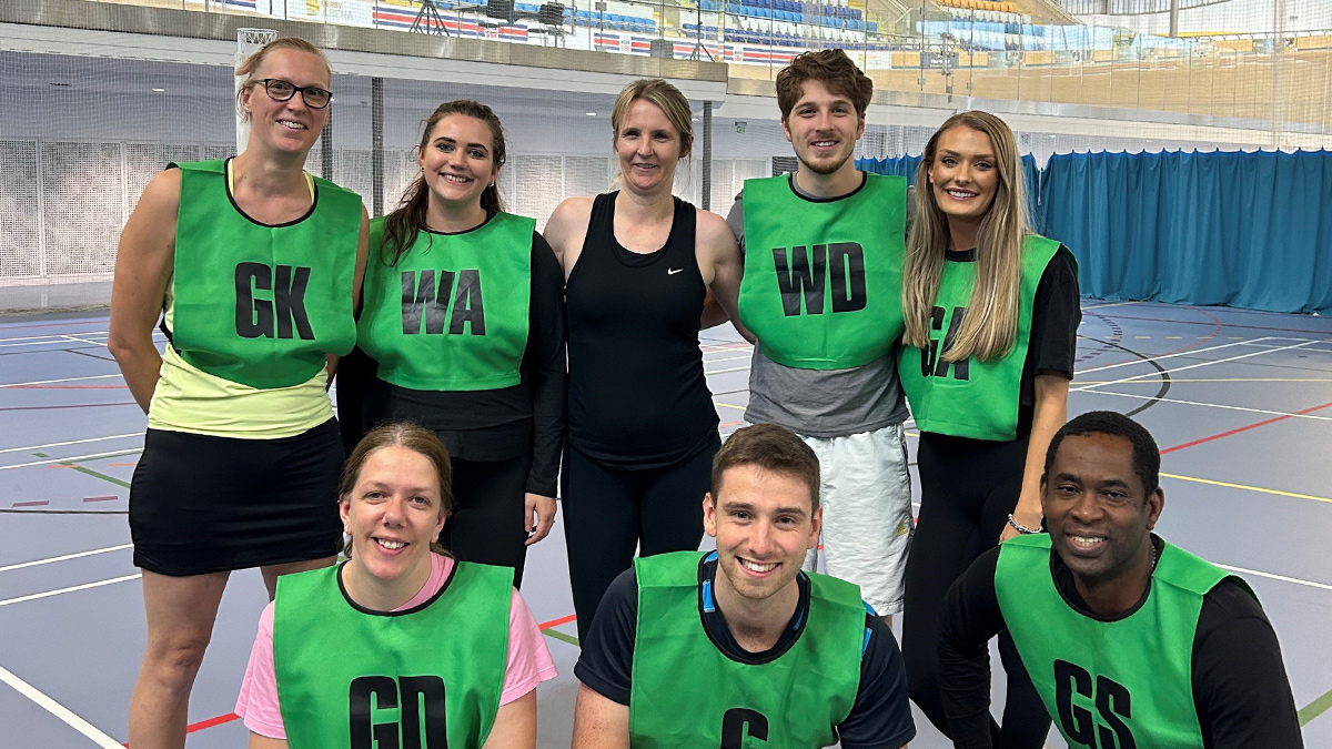 Team of 8 in green netball bibs on a netball court at Derby Arena
