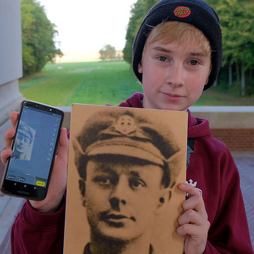 Student holds photo of soldier  with memorial field in background