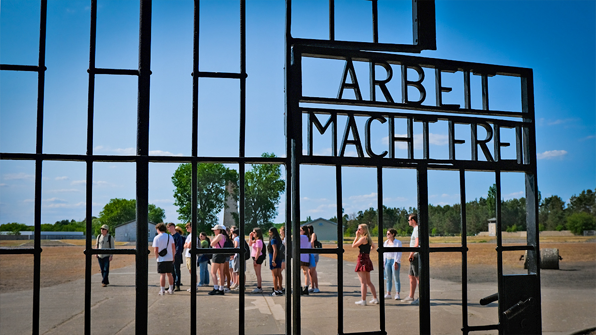 Gates of Auschwitz in the foreground, with students from a Rayburn Tours history tour in behind them.