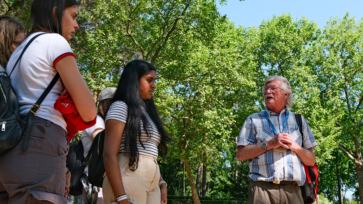 Trevor Booker talks to students outside on a sunny day whilst on a history tour.