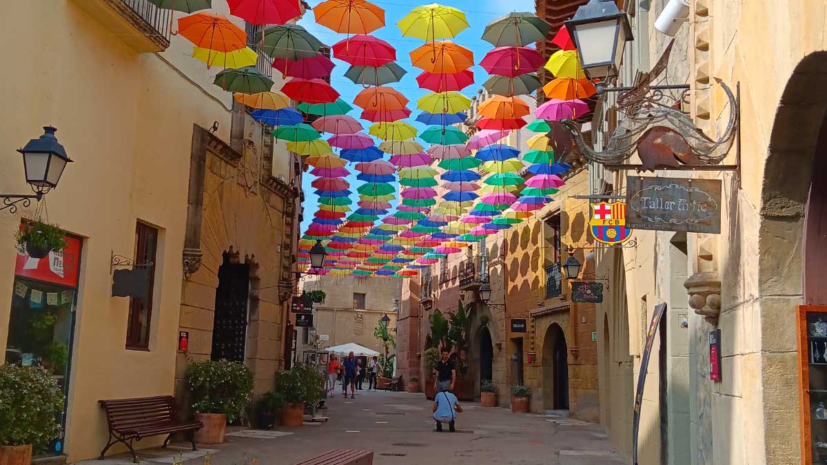 Poble Espanyol street with colourful umbrellas crossing the buildings from roof to roof