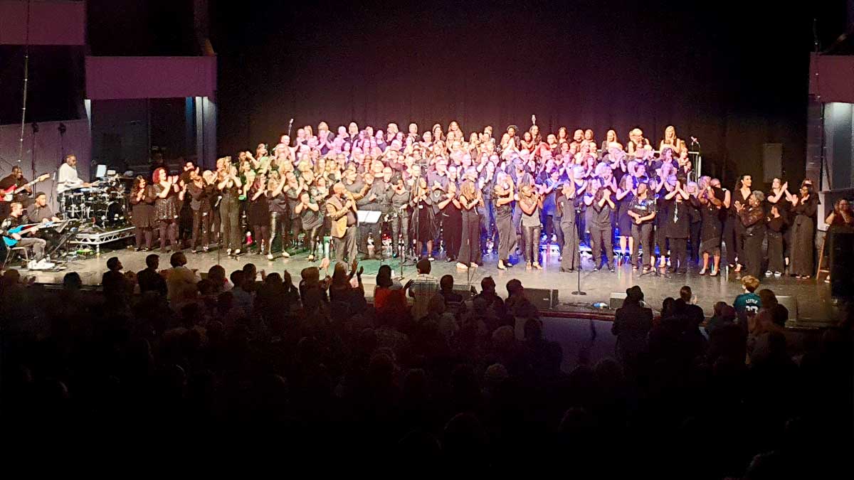 Wellingborough Gospel Choir on stage as a group clapping with live band at the side.