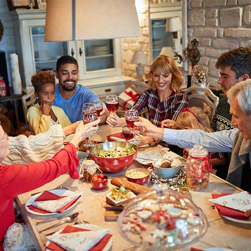 Family having Christmas dinner at home with friends is one of the Christmas traditions from around the world.