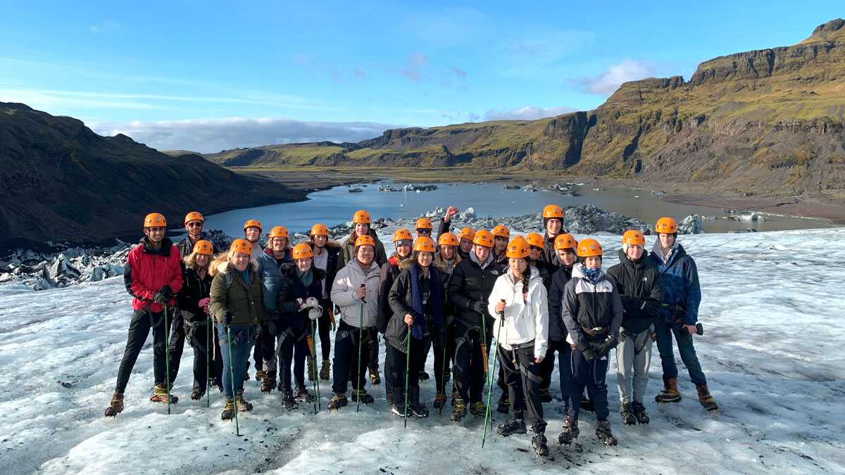 School group on Sólheimajökull glacier with a mountain backdrop.