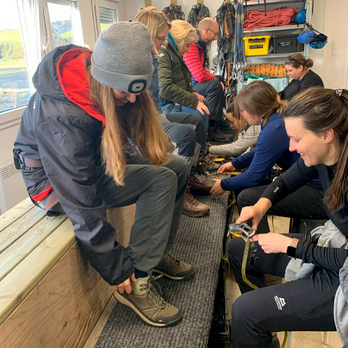 A group of people changing shoes and sat on a platform in a room