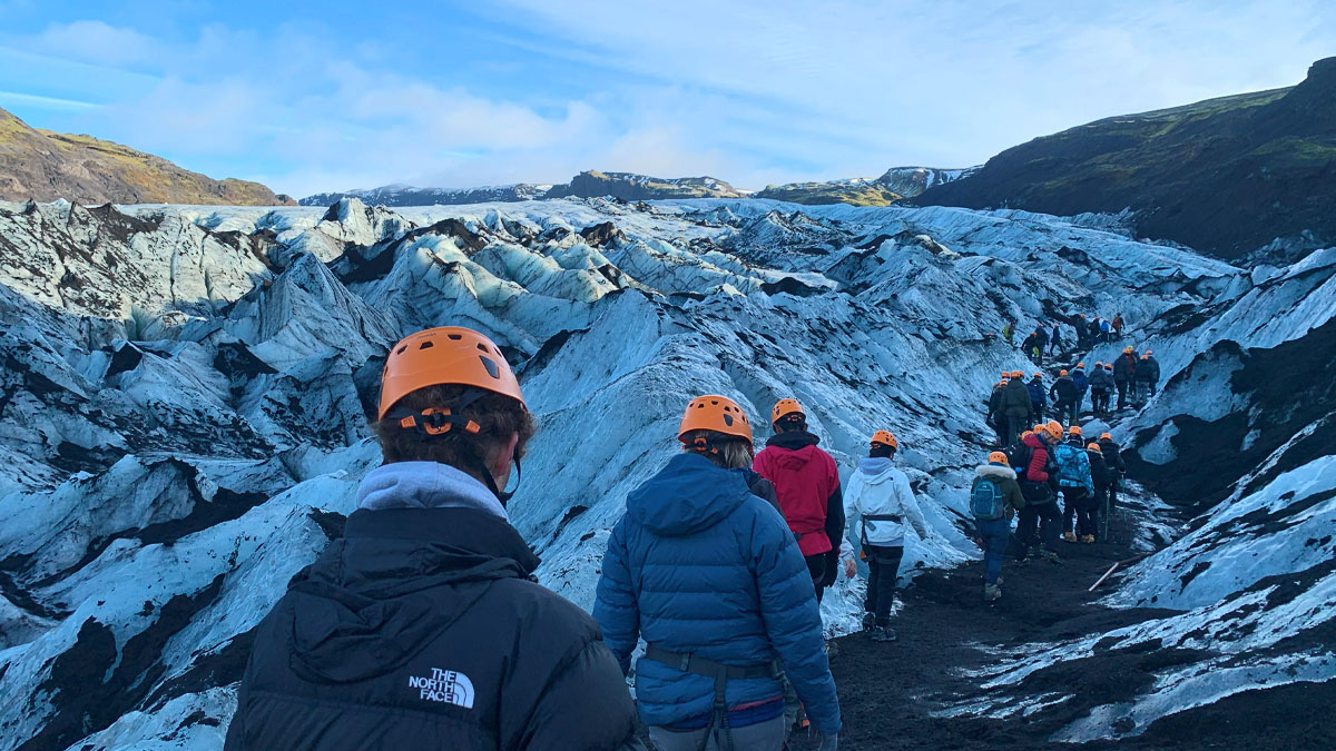 A group of students with helmets on walking up the Sólheimajökull glacier, landscape of ice. 