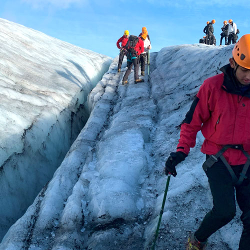 Group of people at the top of the Sólheimajökull glacier, a person is walking back down it. 