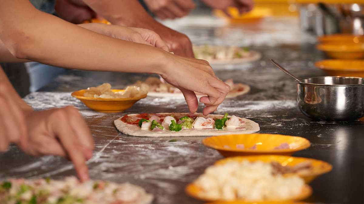 Hands on a kitchen counter making pizza.