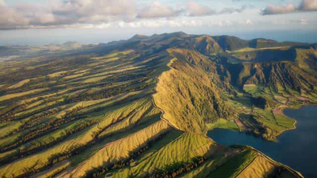 Air shot of the undualting hills and jutting coastline of the Azores