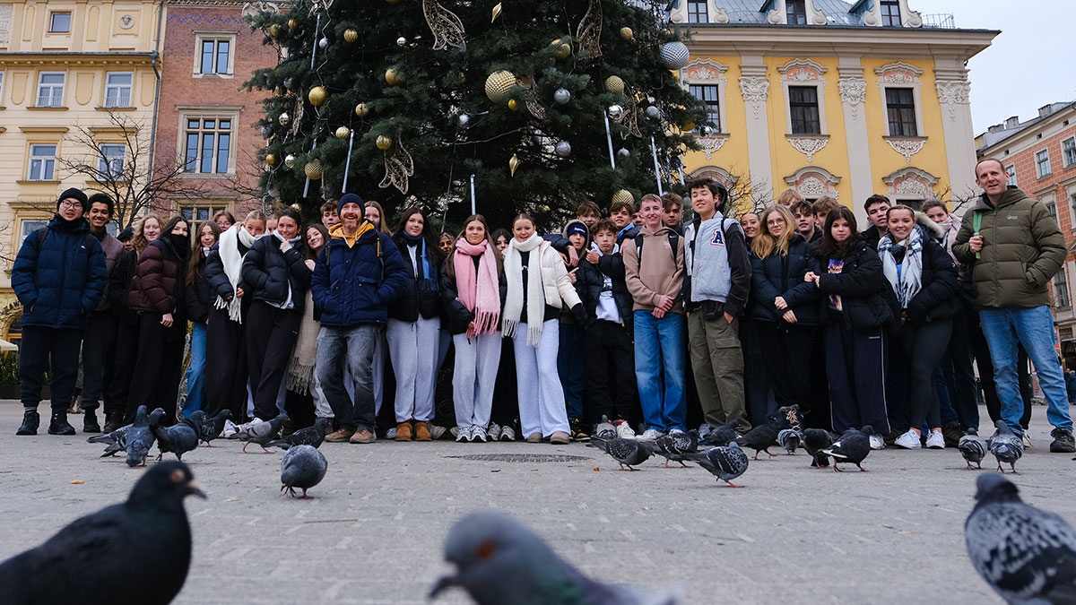 School group pose for a photo in front of a Christmas Tree in Krakow market square.