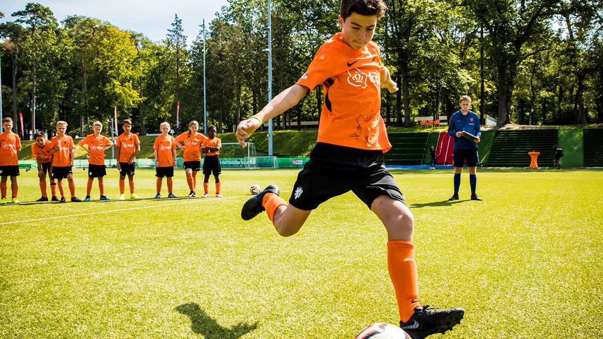Player kicking a ball on a football pitch at KNVB Campus