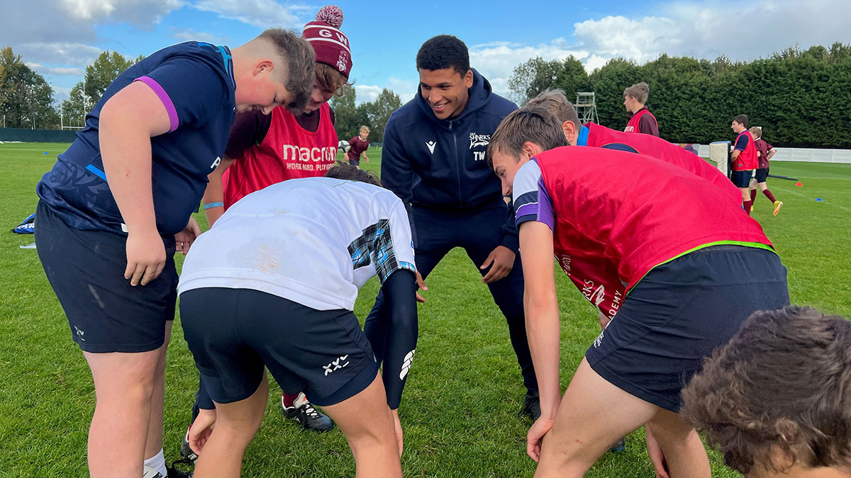 Players huddling with Sale Sharks player Tristan Woodman