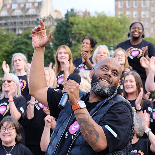 Wellingborough Gospel Choir singing in the Mound in Edinburgh. Conductor at the front and chorists at the back. 