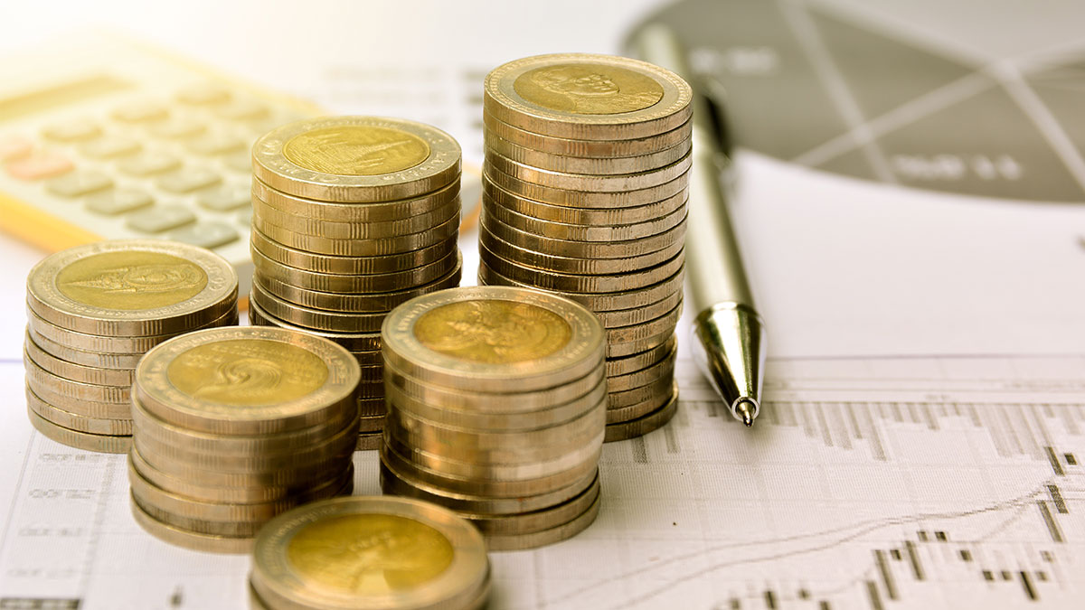 Stack of coins with a calculator and pen
