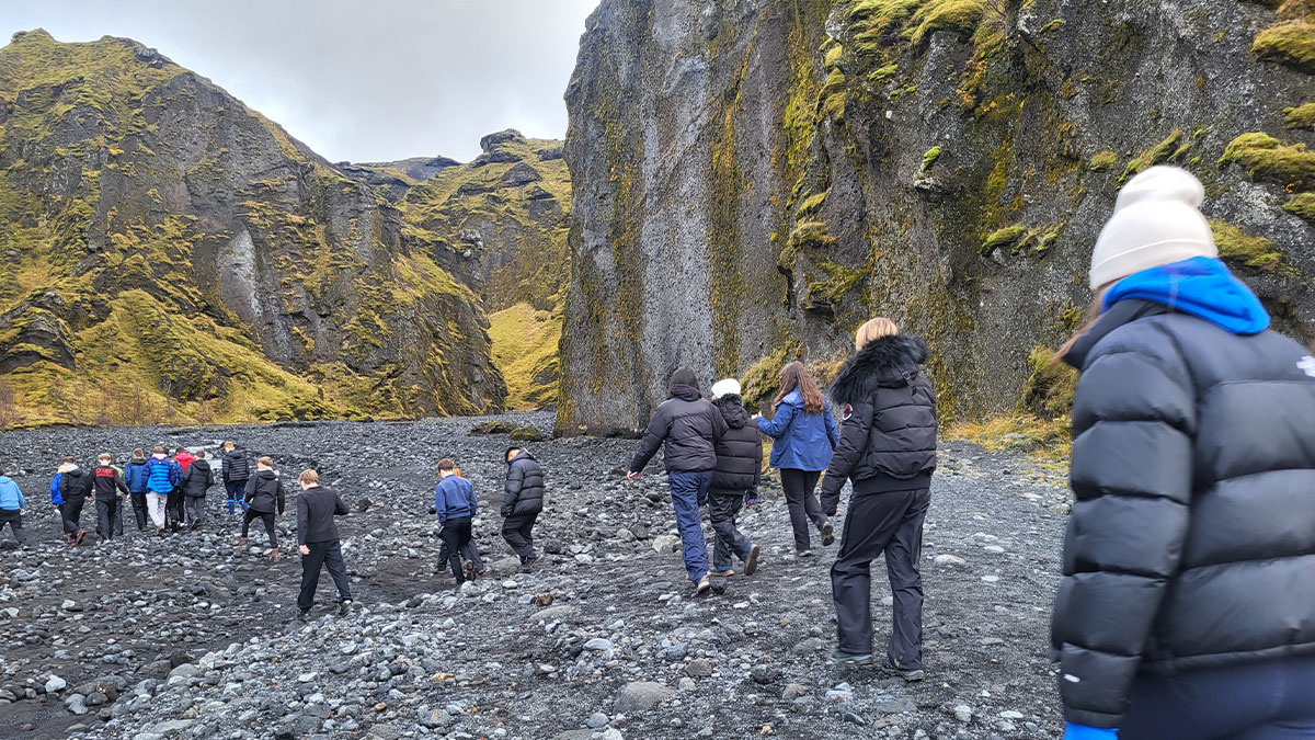 Students walking towards a waterfall in Iceland