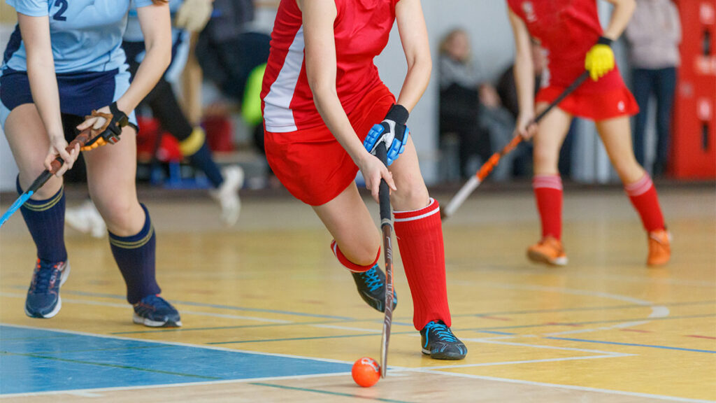 Young woman hockey player in attack at indoor hockey match