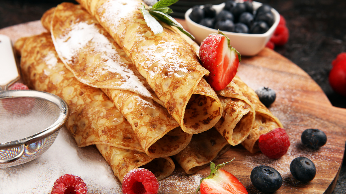 Homemade crepes with raspberries and mint on rustic background
