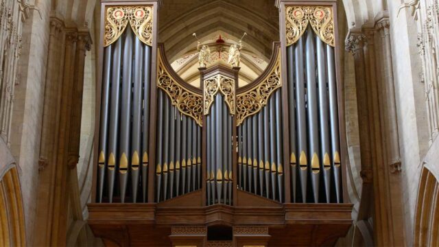 Wells Cathedral Organ. Organ pipes in Wells Cathedral, England. On top of the pipes there are two gold angels playing trumpets.